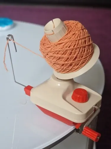 Orange yarn ball taking shape on the Skeinwright ball winder spindle, photo from a verified buyer